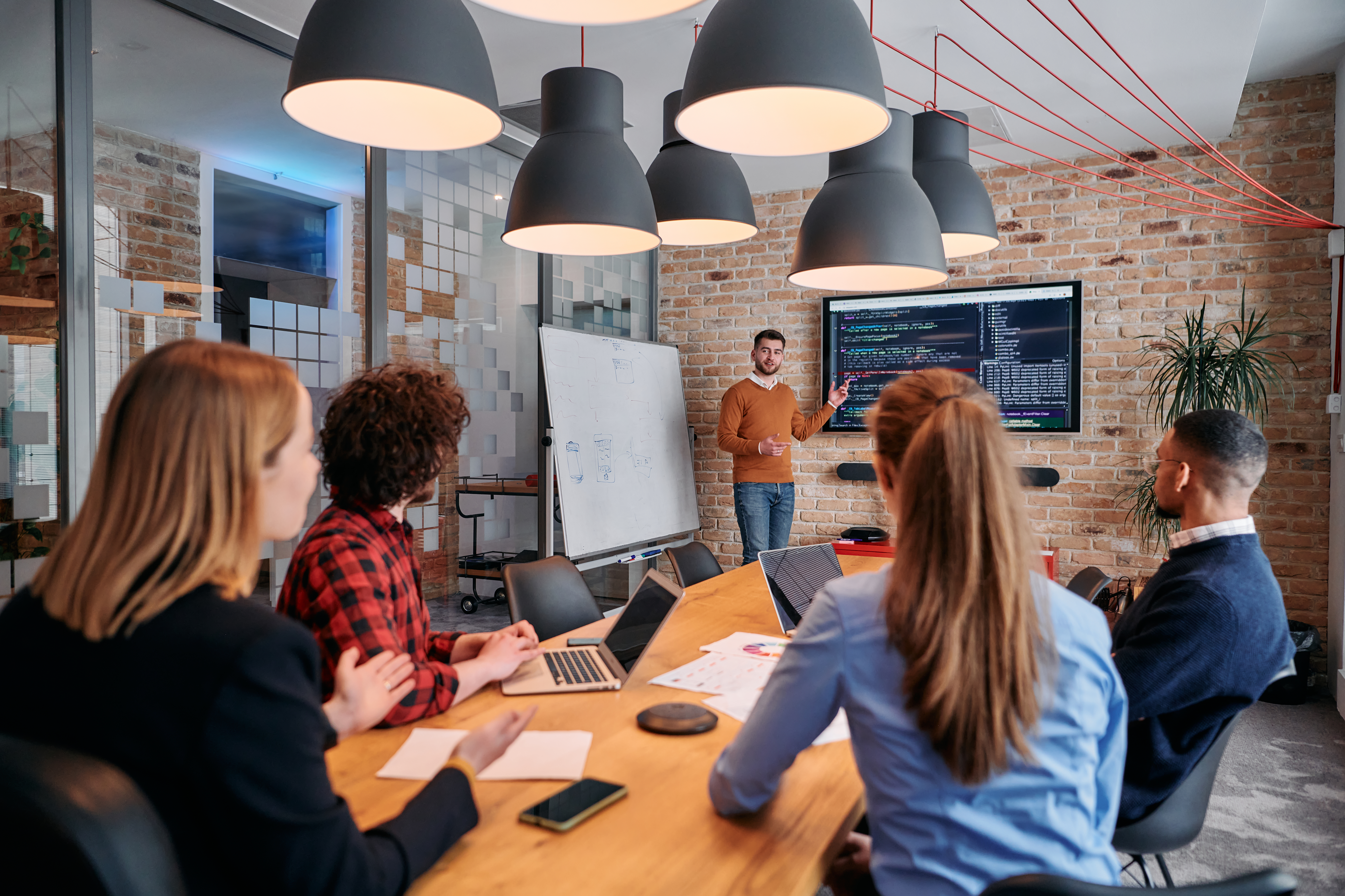 In a corporate setting businessman leads a meeting, passionately presenting a business plan to his attentive team, fostering collaboration and strategic thinking.