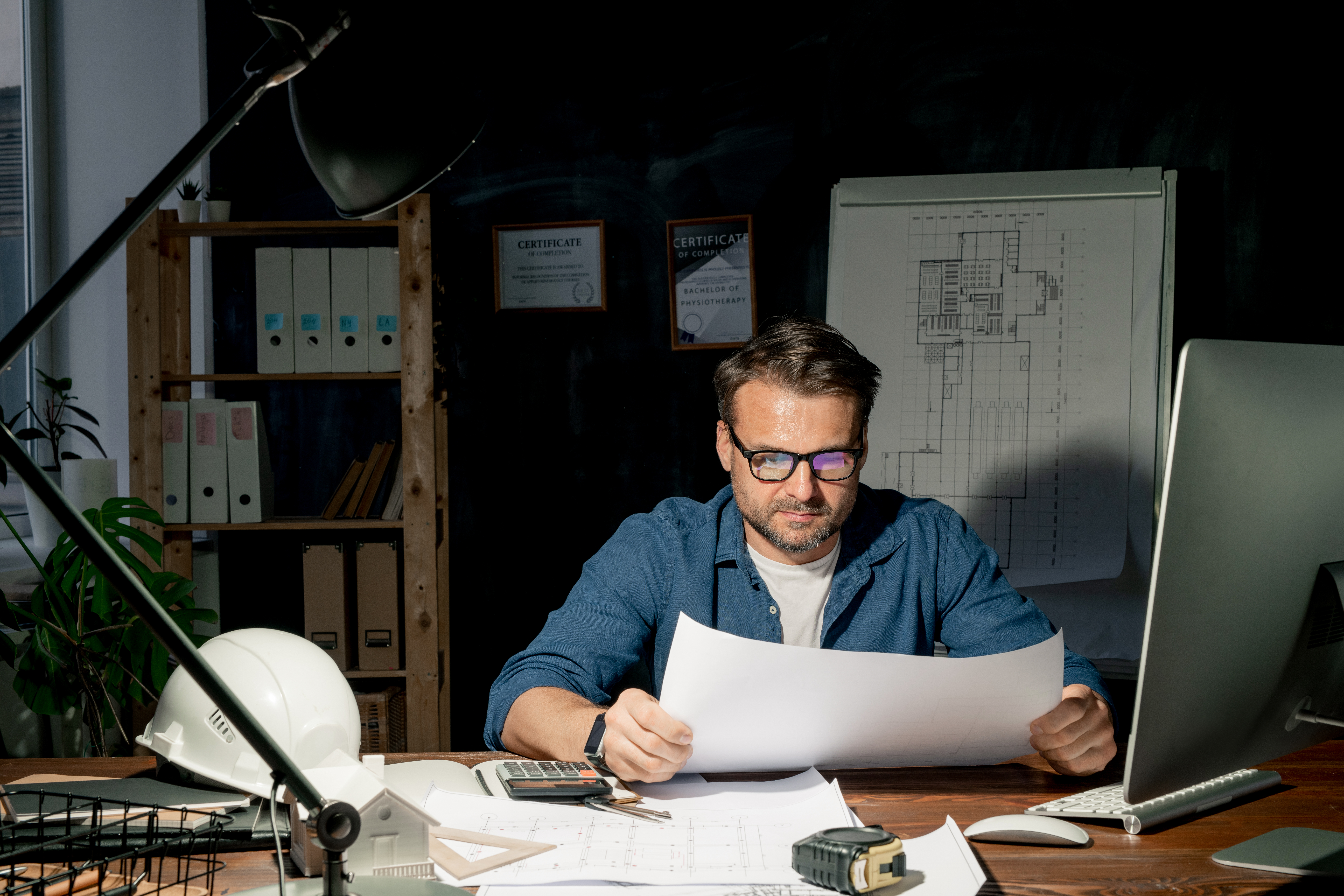 Mature architect looking at sketch while working in office late in the evening